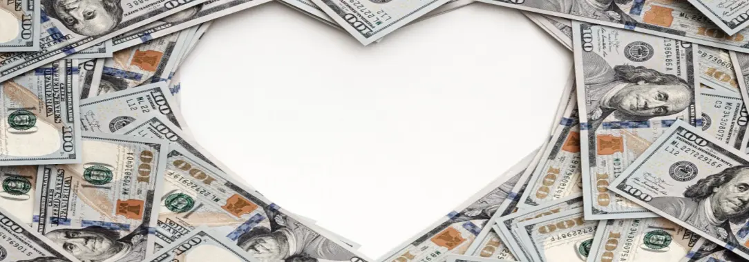 Dollar bills laid out on a white surface creating a heart shape