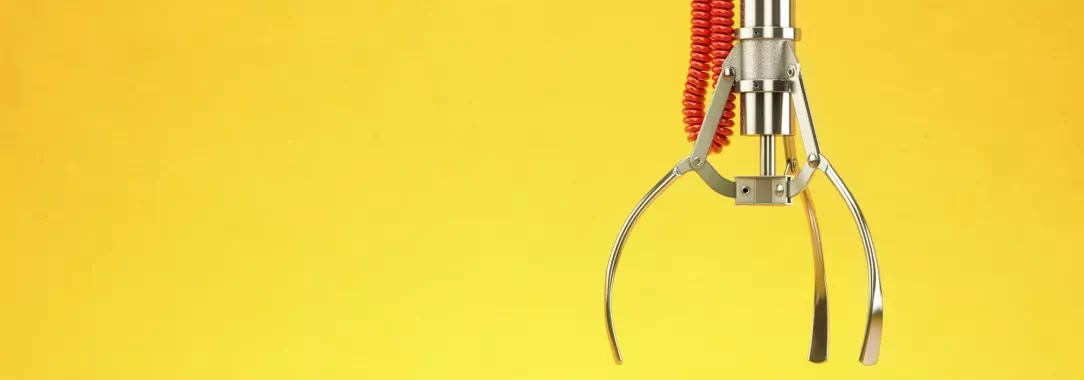 An image of a mechanical claw machine claw on a yellow background 