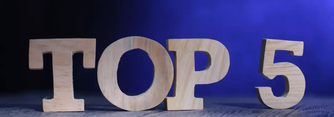 A photo of a “Top 5” carved from wood on a blue background under a spotlight 