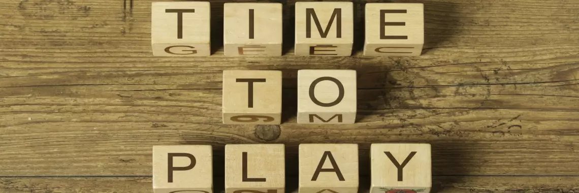 An image of wooden cubes spelling out “time to play” on a wooden surface 