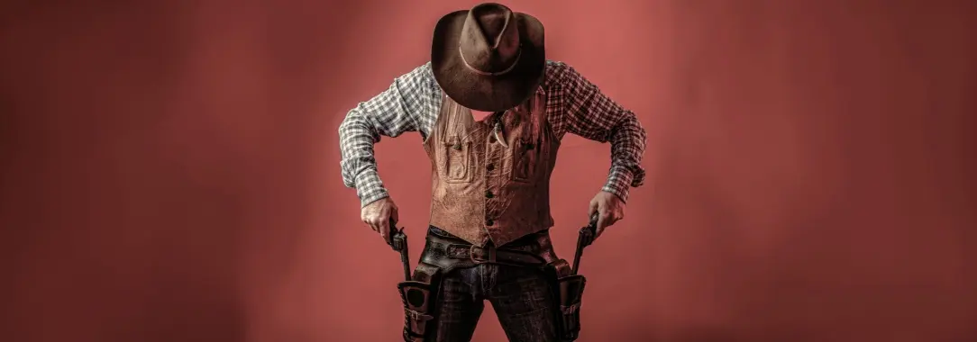 A photo of a cowboy, with his head down drawing both handguns, isolated on a dark red background