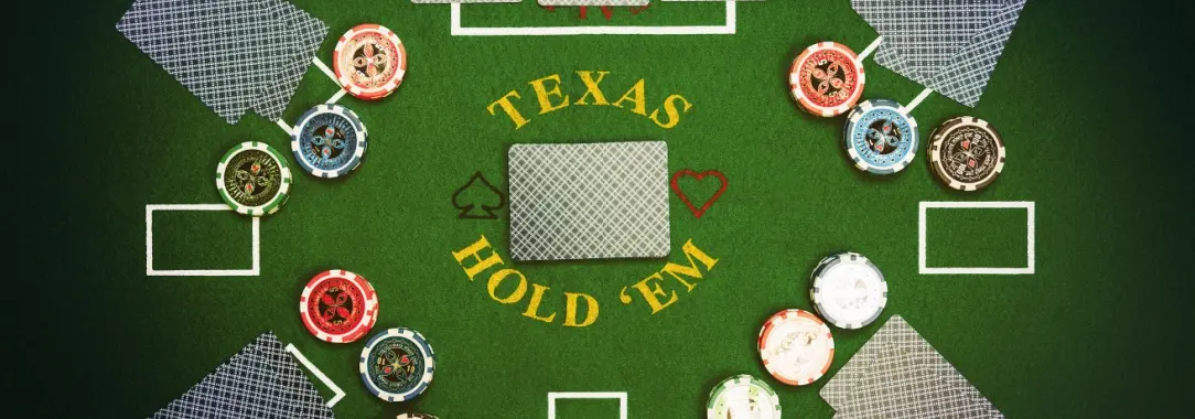 an overhead view of a poker table with chips and cards and Texas Holdem at the center of the table