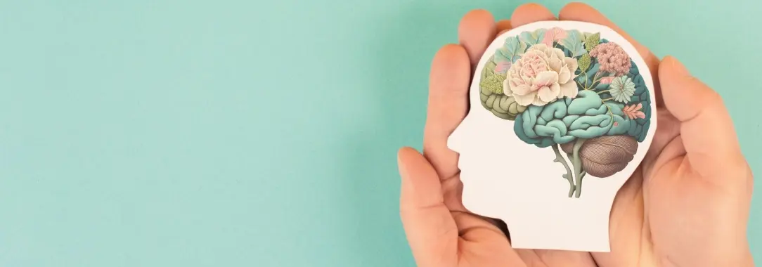 a hand holding a paper cutout of a head seen sideways and inside the head are all of the parts of a person's brain