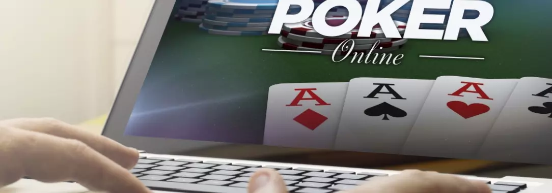 a man playing poker on his laptop. There are four aces on the screen and the words poker online.