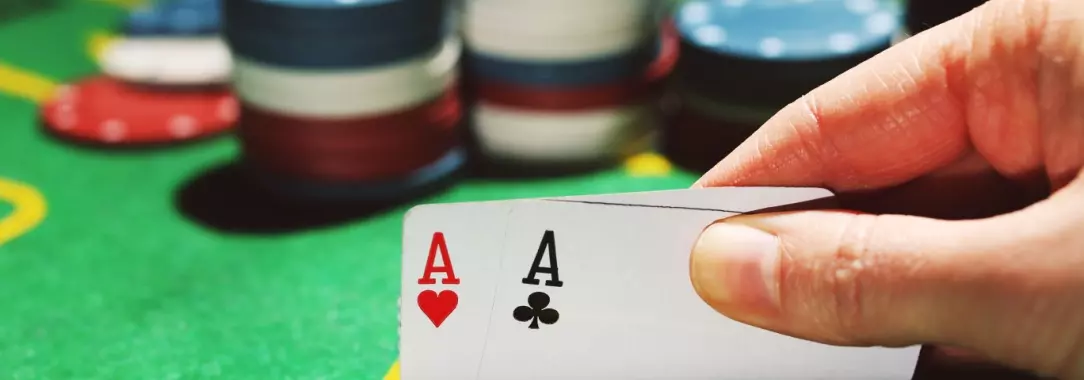 a woman holding pocket aces in poker.  The picture shows poker chips on the table.