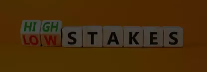 Wooden blocks spelling the words high and low stakes on an orange background