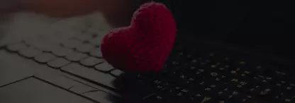 A closeup of a red knitted heart on a laptop keyboard, faded