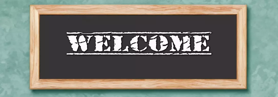 A photo of a framed sign with the word welcome in white on a black background