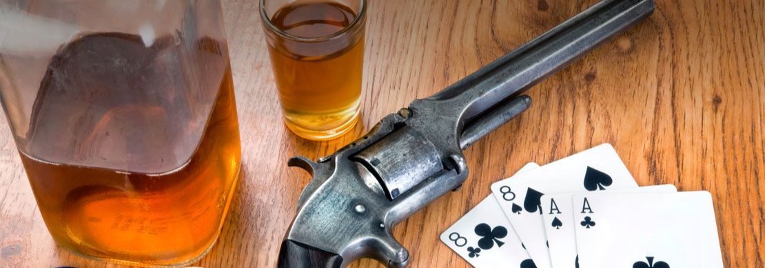 whisky, cards, gun and chips on a wooden table